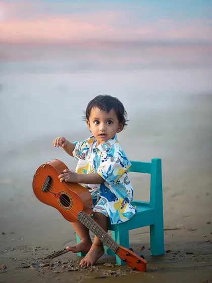 Exploring the textures of the guitar and the sand. Outdoor shoots are a wonderful sensory experience for little ones, leading to authentic, curious expressions.