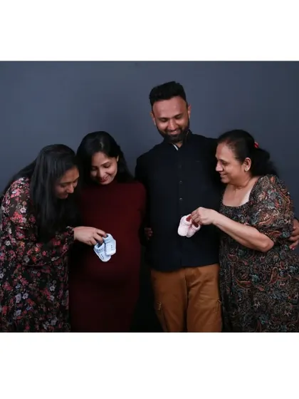 The whole family looks down at the tiny baby shoes, a sweet and symbolic gesture of welcoming the new member.