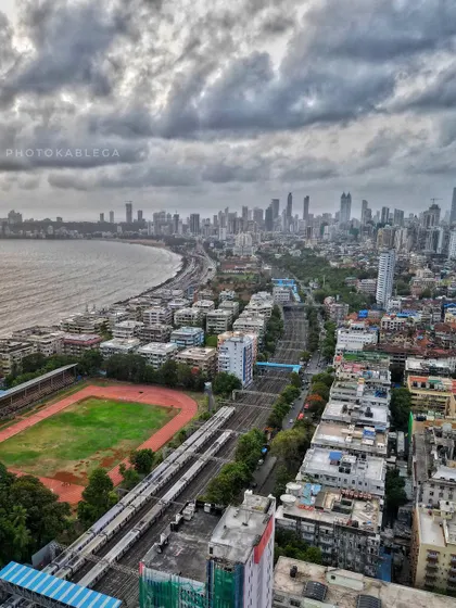 This high-altitude view shows the curve of Marine Drive, the railway tracks, and a sports ground, painting a complete picture of urban life along the coast.
