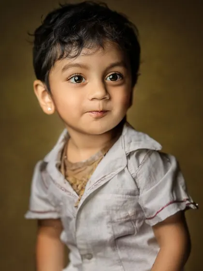 A handsome portrait of a young boy with a thoughtful expression. The classic lighting and background give it a timeless, fine art quality.