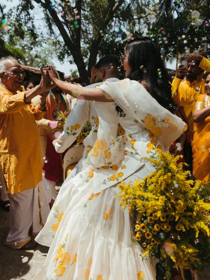A moment of dance and celebration during the Haldi event, with the couple surrounded by joyful family and friends under a shower of petals.