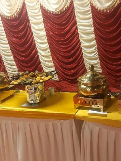 A buffet table with appetizers and main courses set against a festive red and white backdrop, perfect for a wedding or traditional ceremony.