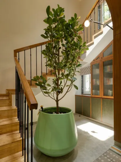 The sunlit stairwell is more than just a transition space; it's a quiet reading nook with a built-in bookshelf under the stairs.