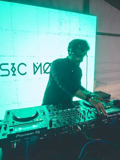 At the decks during a Navratri festival, with my logo on the screen. I provide a professional setup for any festive event, ensuring great sound and visuals.