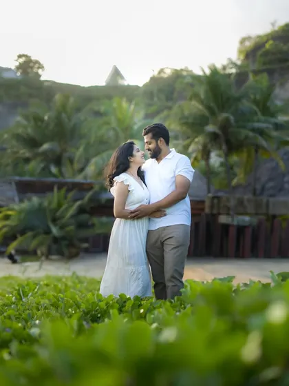 A candid moment during the golden hour, surrounded by a field of green by the sea. The soft light and natural setting create a relaxed and romantic atmosphere.