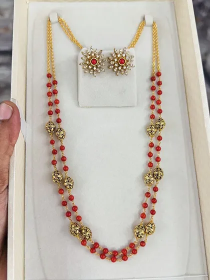 Another look at the traditional red beaded necklace set with star-shaped studs. The craftsmanship on the golden beads is exceptional, adding to its premium feel.