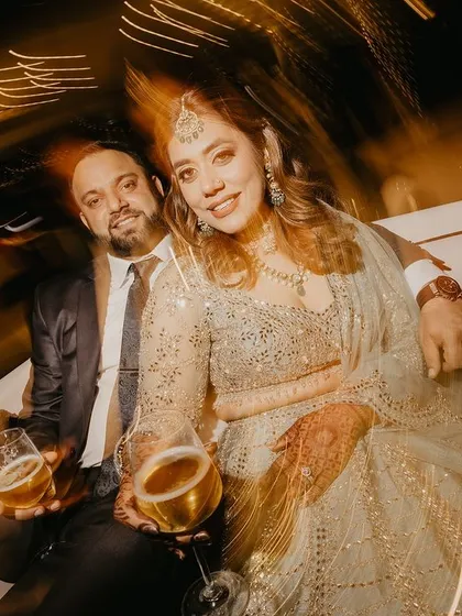 A cool, relaxed portrait of the couple enjoying a drink together. The motion blur and warm lights create a vibrant party atmosphere.