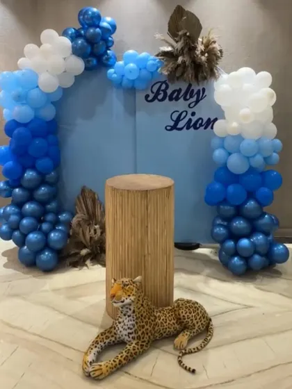 The main backdrop for our "Baby Lion" welcome party. A cute leopard prop, a wooden pedestal, and a blue and white balloon arch created a fun and playful jungle vibe.
