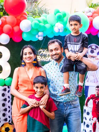 A vibrant family photo from an 8th birthday party. The football and video game-themed decorations create a fun and energetic backdrop for this happy family portrait.