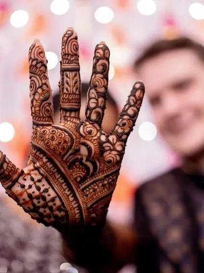 The bride showing off her completed mehendi design. The rich, dark stain is a beautiful part of the bridal look, symbolizing love and good fortune.