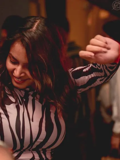A woman in a zebra-print top, dancing with a smile. She's bringing her own wild energy to the party.
