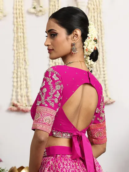 The back of this fuchsia blouse reveals a modern keyhole design with a delicate tie-up, blending contemporary style with traditional elegance. Every angle is designed to be a statement.