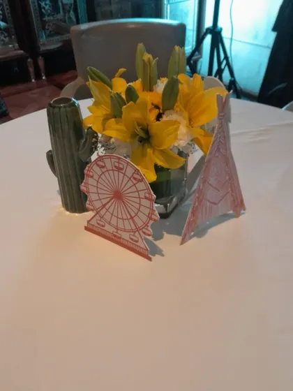 It's all in the details. This "Babychella" themed table centerpiece includes fresh flowers and custom-cut props like a ferris wheel and a teepee, perfectly matching the party's vibe.