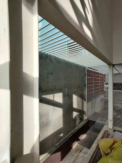 The louvered screens create a layered facade that is both functional and aesthetically pleasing.