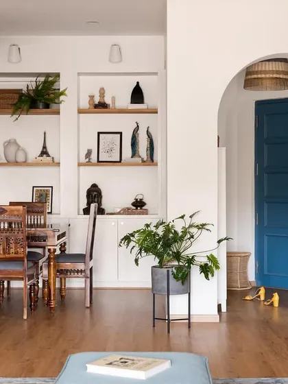 By removing an old cabinet and opening up a wall, we created this beautiful arched view into the dining room, complete with custom shelving. The bold blue door adds a pop of personality and draws the eye through the space.