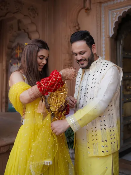 A playful moment where the bride helps the groom with his 'kalire,' a traditional and fun part of the pre-wedding rituals.