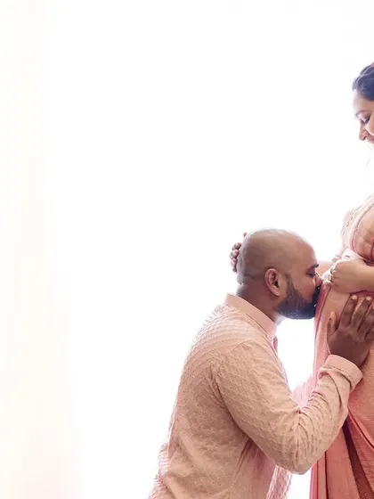 A gentle kiss for the baby. This high-key photograph is full of light and love, creating a timeless memory for the expecting parents.