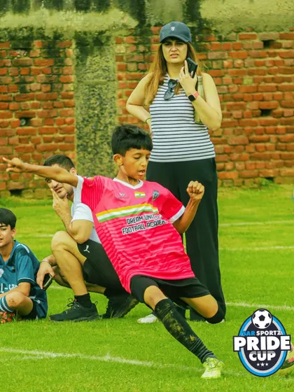 The passion is real. A young player celebrates a goal with pure emotion, with family watching proudly from the sidelines.