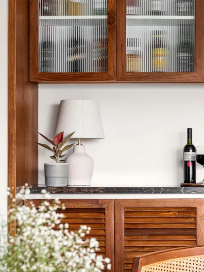 A detail of the 'Gulmohar' bar unit, highlighting the combination of fluted glass, louvered shutters, and a dark marble countertop.