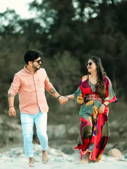 A happy couple walks hand-in-hand along a sandy path, sharing a smile. This candid shot perfectly captures the joy and ease of their relationship.