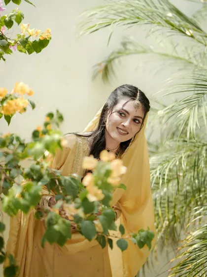 A duplicate of the bride peeking through bougainvillea flowers, her gentle smile and the natural frame creating a soft and romantic portrait.