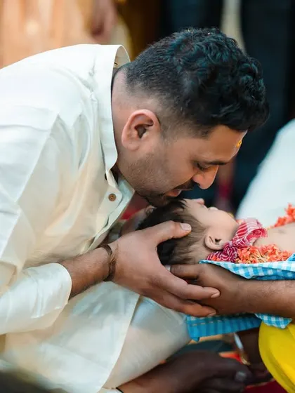 A father's gentle kiss on his baby's forehead is a moment of pure love. I specialize in capturing these unscripted, emotional interactions during family events.