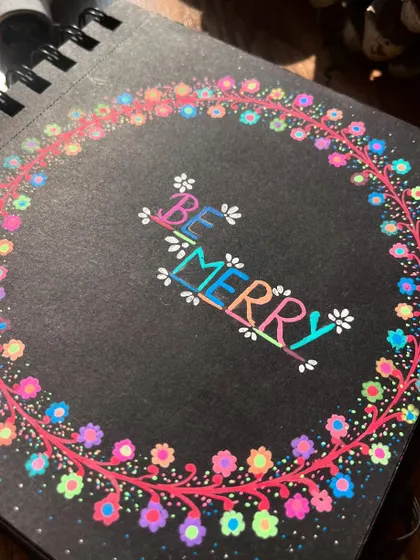 A close-up of the "Be Merry" floral wreath.