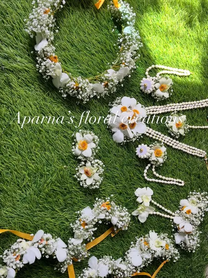 A full view of the white and yellow floral set. It includes a tiara, necklace, earrings, and haath phool.