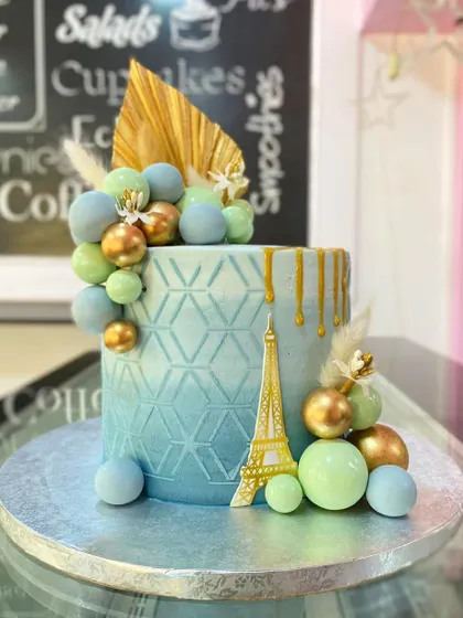 This angle of the Paris-themed cake showcases the beautiful color gradient and the placement of the delicate dried pampas grass and gold palm leaf.