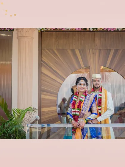 A beautiful couple posing at the entrance of our Kalidas Marriage Hall. The sunburst-patterned wooden doors provide a stunning, modern backdrop for wedding photos.