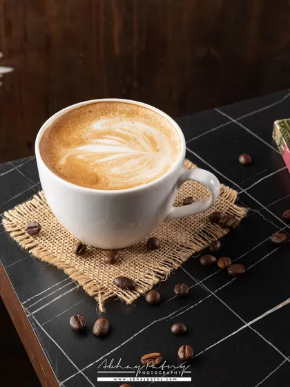 A simple, classic coffee shot. The composition with coffee beans and a book creates a relaxing, "me-time" atmosphere that many customers can relate to.