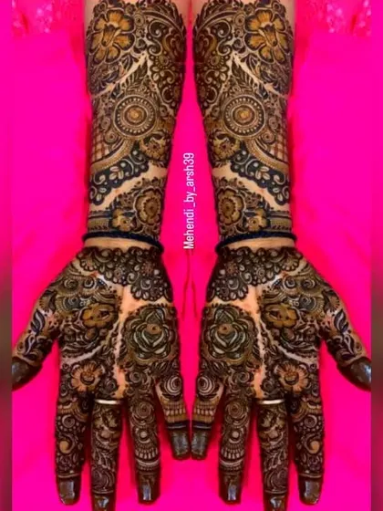 The vibrant pink background makes the dark, natural henna paste pop. This design features bold rose patterns on the palm, a favorite among my brides.