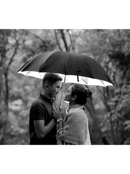 A classic black-and-white romantic photograph of a couple looking at each other under an umbrella, creating a timeless and intimate feel.
