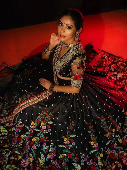 I designed this black lehenga to be captivating and eye-catching. The vibrant, multicolored floral embroidery pops against the dark base, and the sheer embroidered sleeves on the blouse add a touch of modern elegance.