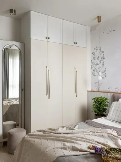 This guest bedroom exudes timeless elegance with classic white and gold accents. A dual-tone wardrobe provides ample storage, while a full-length arched mirror adds a touch of sophistication.