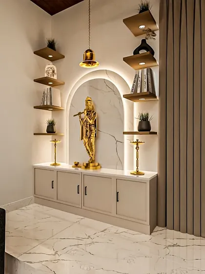 A beautiful and modern pooja room idea. This design features a golden Krishna statue in a backlit arch, surrounded by floating shelves for other deities and sacred books.