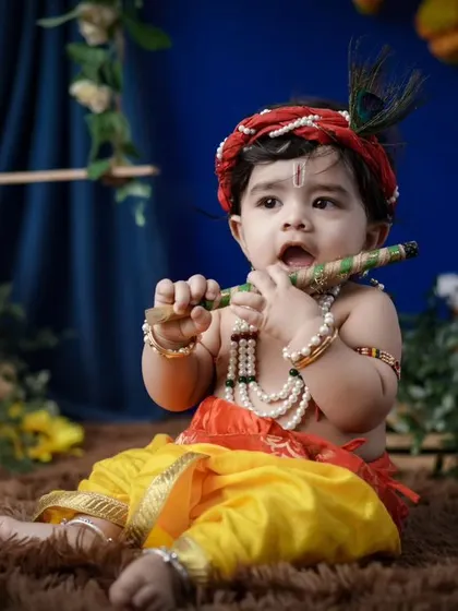 Capturing the innocence of baby Krishna. This portrait shows a younger child dressed in full costume, complete with a peacock feather and flute. The setup is designed to be safe and comfortable for even the smallest babies.