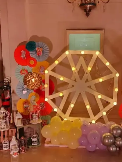 A decorative corner at a carnival party, featuring a light-up Ferris wheel and a lion cutout.