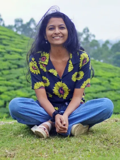 A smiling, cross-legged pose in the green hills of Munnar. This is another great example of a natural, relaxed lifestyle shot for commercial or travel work.