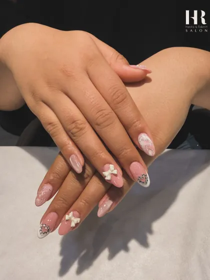 A soft and romantic design with beautiful 3D details. We combined a pink marble effect with delicate sculpted white bows and silver heart charms for a sweet and elegant manicure.