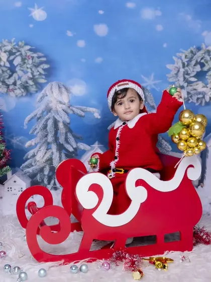 Another angle of the Christmas sleigh setup, capturing a happy baby holding ornaments. I create a fun and safe environment for babies to interact with the props.