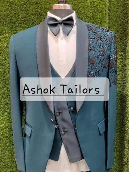 A teal suit with black floral embroidery on the shoulder.