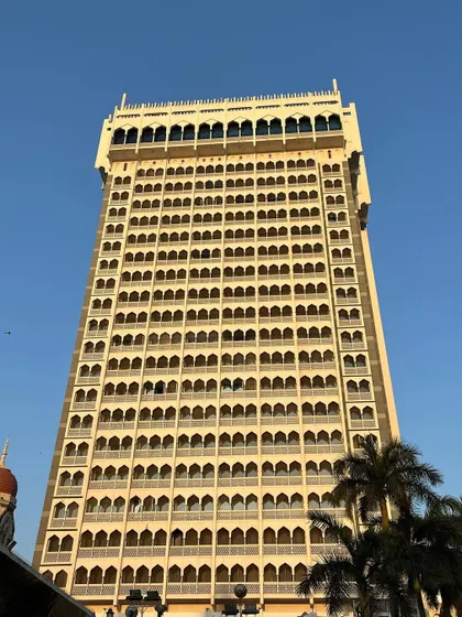 A low-angle view of the modern tower wing of the Taj Mahal Palace hotel, showcasing its distinct architectural style.