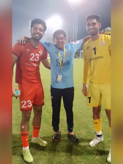 An academy player gets a photo with two professional players after a Reliance Foundation Development League match.