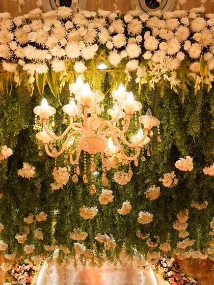 A close-up of the canopy of white carnations and greens, with elegant chandeliers. This decor was curated for a perfect modern white wedding.