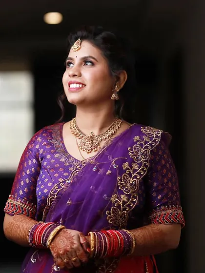 Sheela looking up, radiant and happy, during her engagement ceremony. Her makeup is designed to look beautiful from every angle.