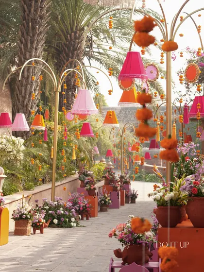 The entrance walkway to the Haldi, lined with colorful lampshades, marigold strings, and floral arrangements. It created a festive and welcoming pathway for guests.