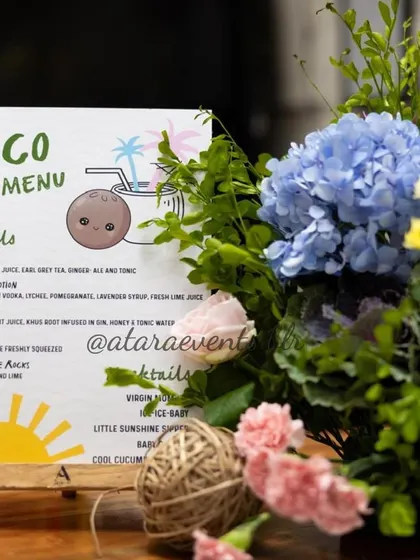 The "Coco Bar Menu" from a tropical-themed baby shower. The menu features creative, themed cocktail and mocktail names, adding a fun and personalized touch to the beverage station.