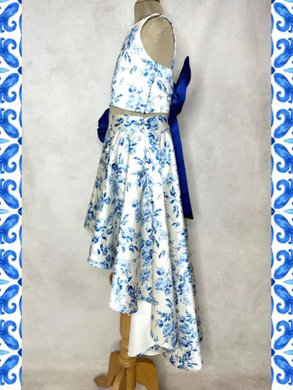 The perfect brunch outfit. This beautiful blue and white floral print set features a high-low skirt and a matching crop top, with a stunning statement bow at the back.
