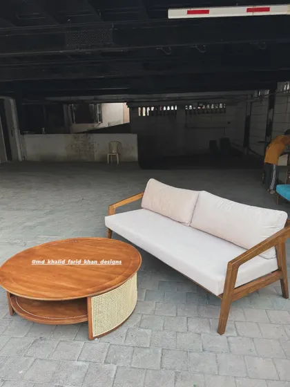 A mid-century modern living room set featuring a solid wood sofa and a round coffee table with a woven cane shelf.